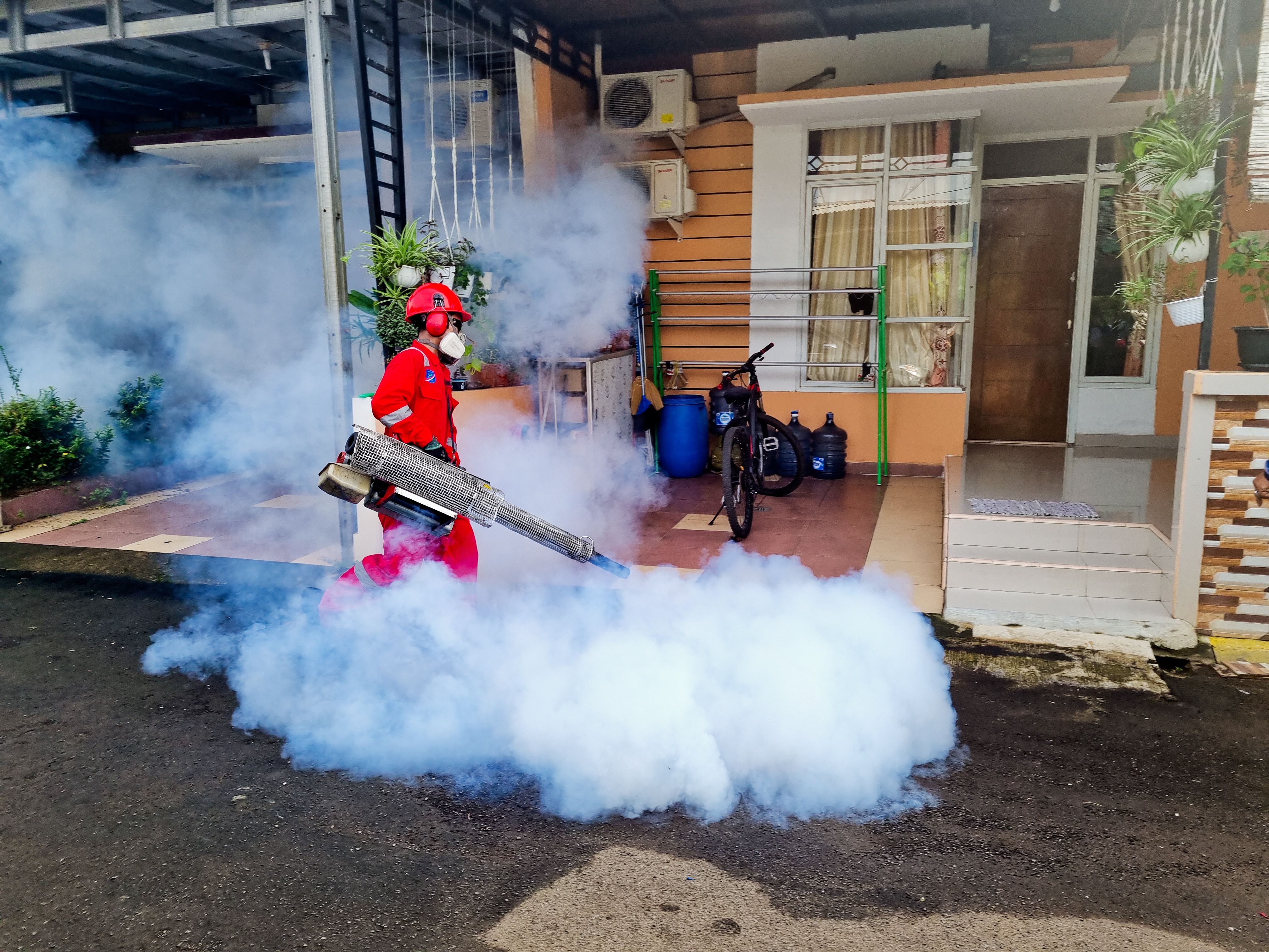 Pest control technician fogging outside a residential home