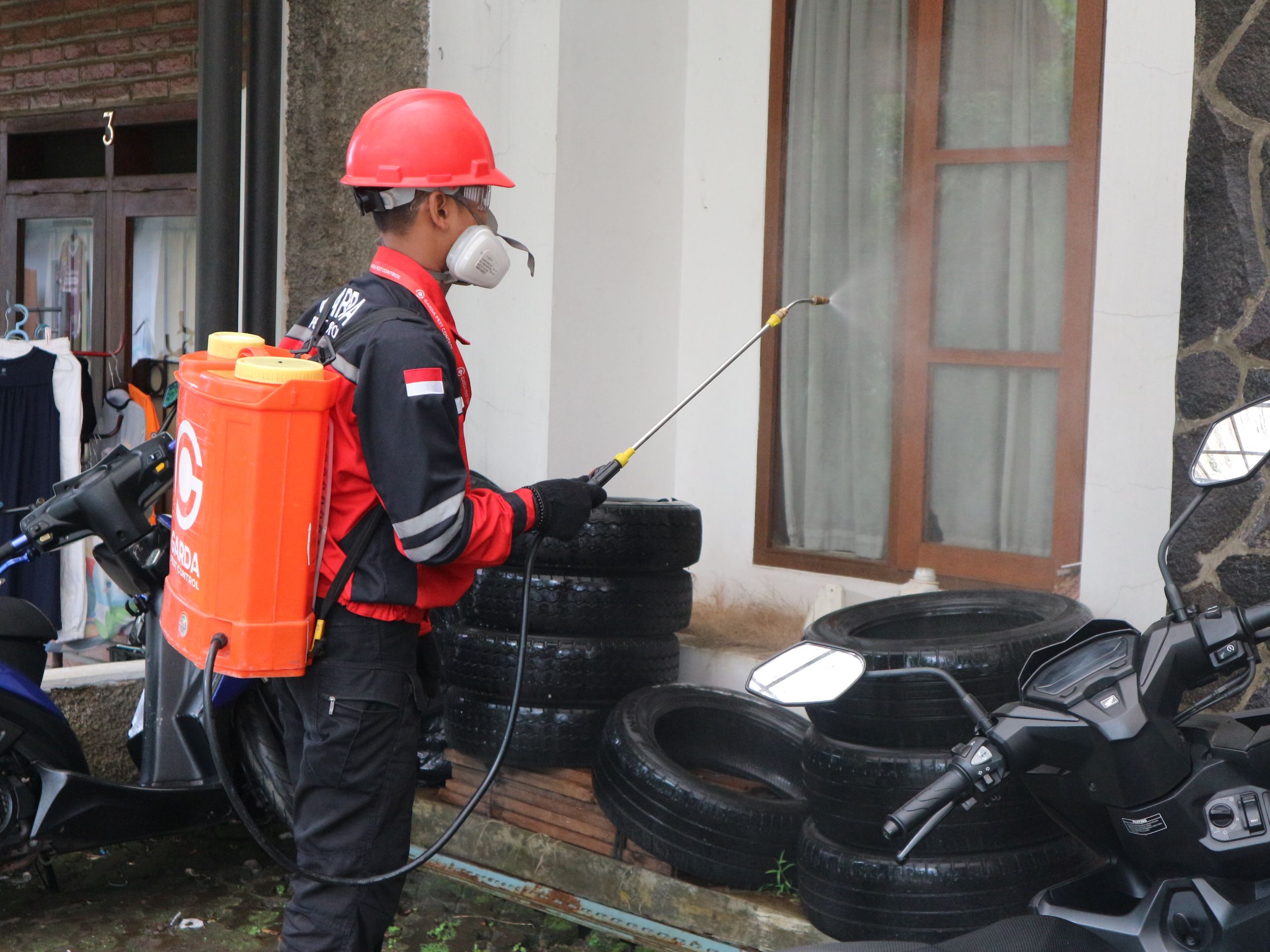 Technician applying pest treatment to the exterior of a residential home