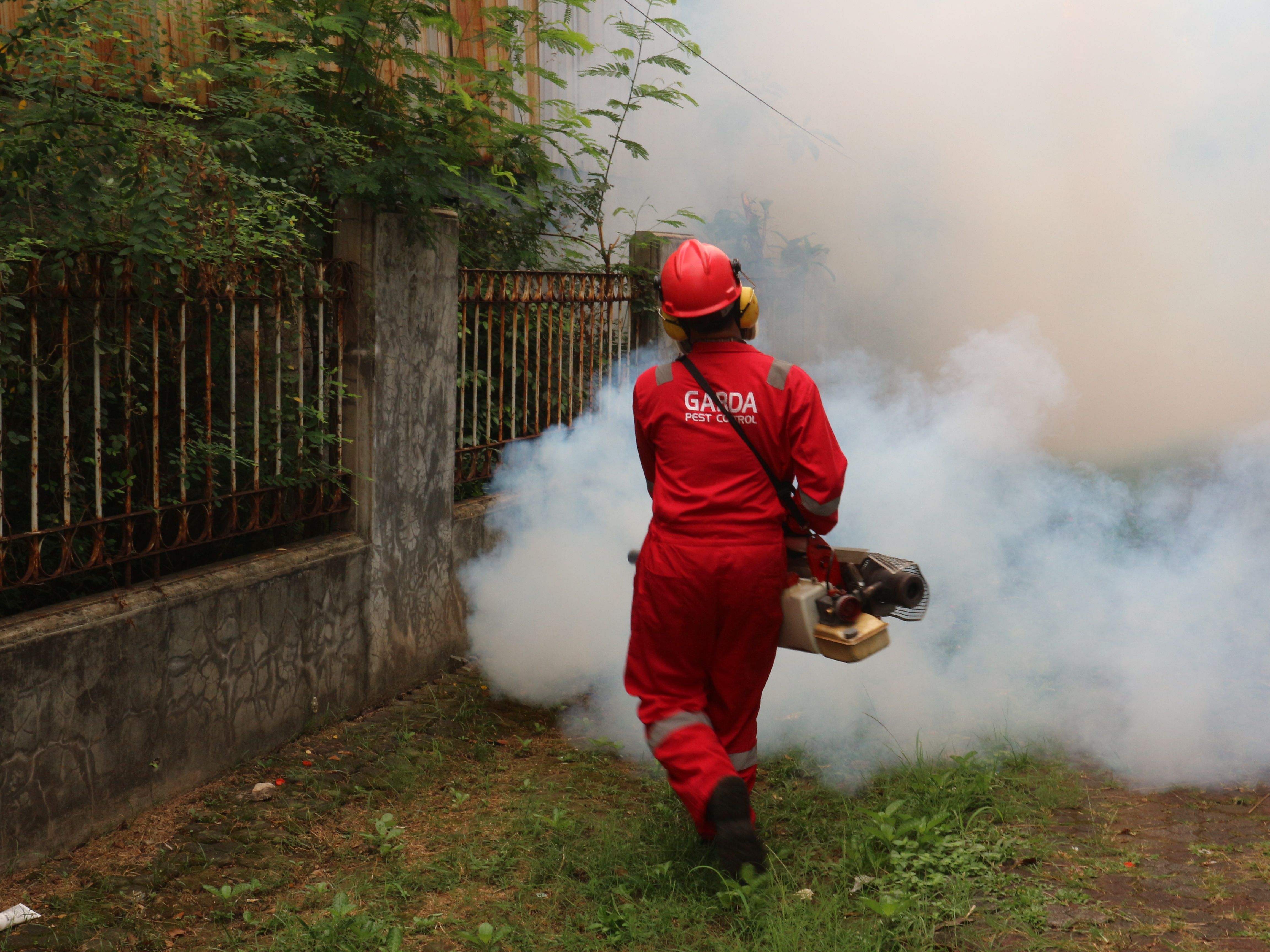 Pest control technician fogging an outdoor service area